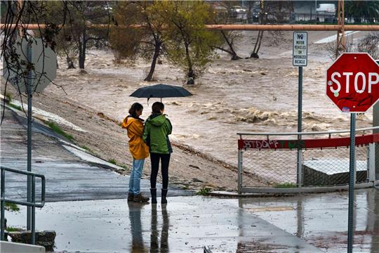 Menschen beobachten die großen Mengen an Regenwasser im Los Angeles River.