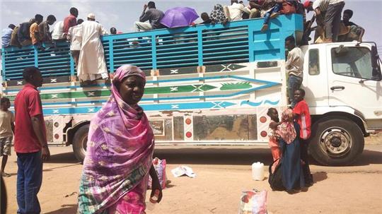 Menschen besteigen einen Lastwagen, um eine Stadt im Sudan zu verlassen.