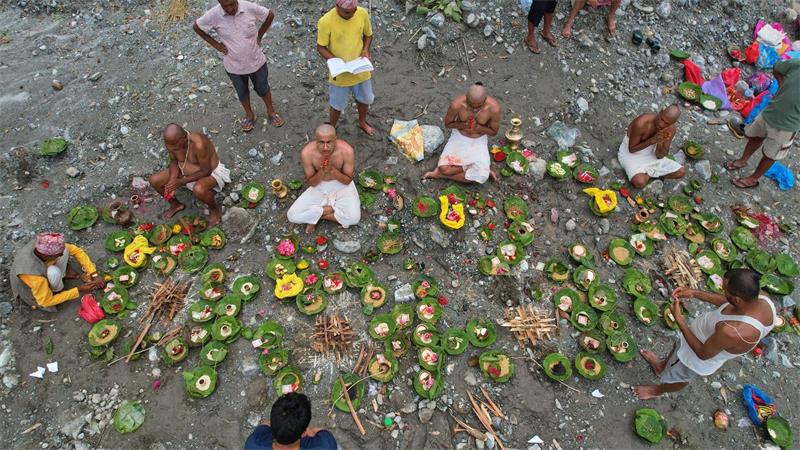 Menschen, deren Angehörige nach den Sturzfluten weiterhin vermisst werden, vollziehen am Ufer des angeschwollenen Trishuli-Flusses im nepalesischen Distrikt Nuwakot Rituale im Anschluss an symbolische Bestattungszeremonien.