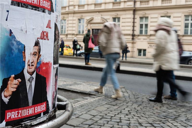 Menschen gehen an einem Wahlplakat für den Präsidentschaftskandidaten Andrej Babis vorbei, das auf einer Straße in Prag aufgestellt ist.