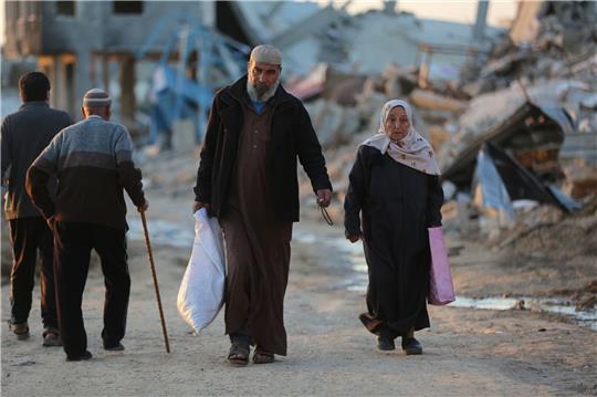 Menschen gehen an zerstörten Gebäuden im Flüchtlingslager Al-Maghazi im Zentrum des Gazastreifens vorbei. Das Bangen um eine Feuerpause vor Ramadan geht weiter.
