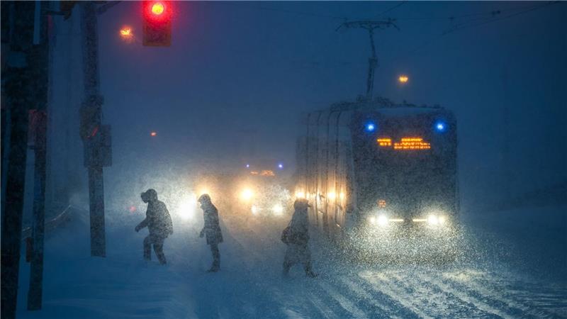 Menschen gehen bei Schneefall durch die Innenstadt von Toronto.