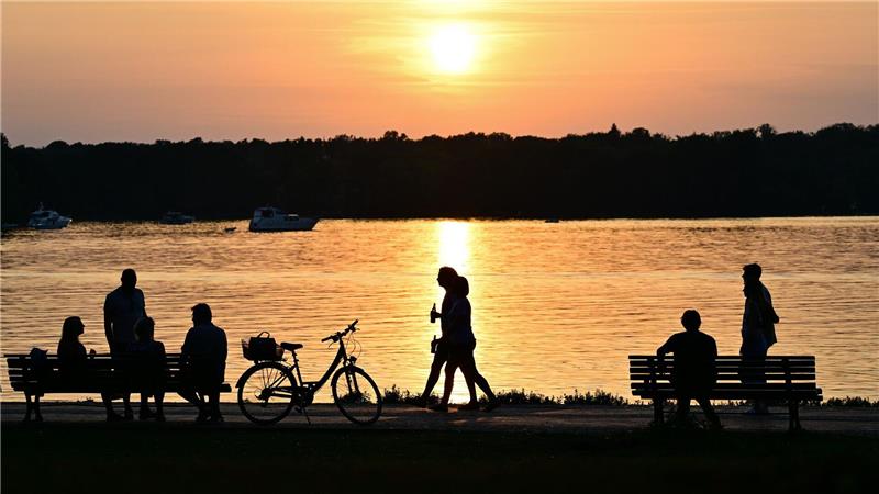 Bilder des Tages Menschen gehen bei Sonnenuntergang am Ufer des Tegeler Sees in Berlin.