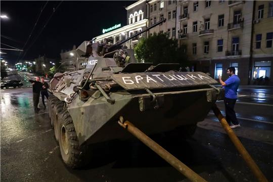 Menschen gehen um ein gepanzertes Fahrzeug des Militärunternehmens Wagner Group mit der Aufschrift «Brother» herum, bevor sie ein Gelände am Hauptsitz des Südlichen Militärbezirks auf einer Straße in Rostow am Don verlassen.