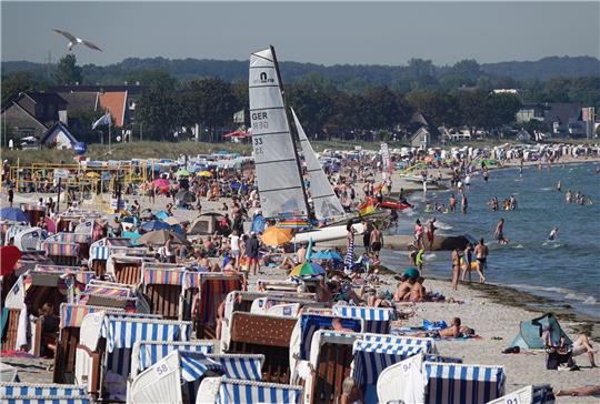 Menschen genießen das Sonnenwetter am Strand der Ostsee.