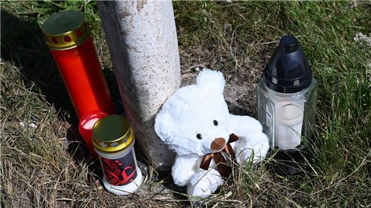 Menschen haben Kerzen und einen Teddybären an der Unfallstelle abgestellt.