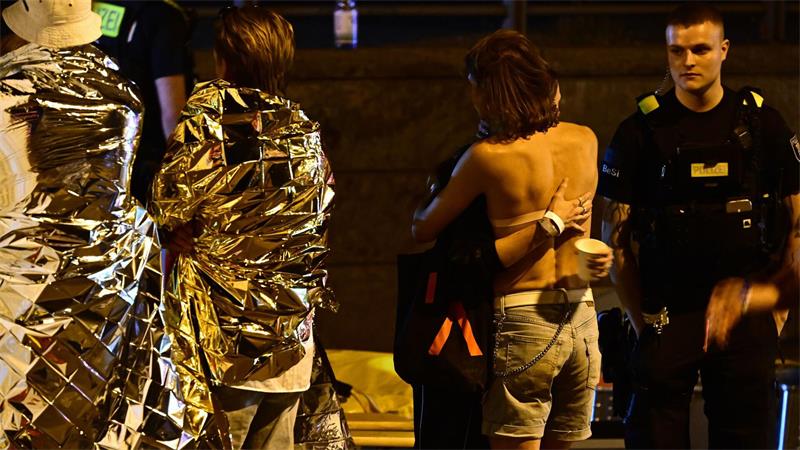 Menschen hüllen sich in Rettungsdecken und umarmen sich.