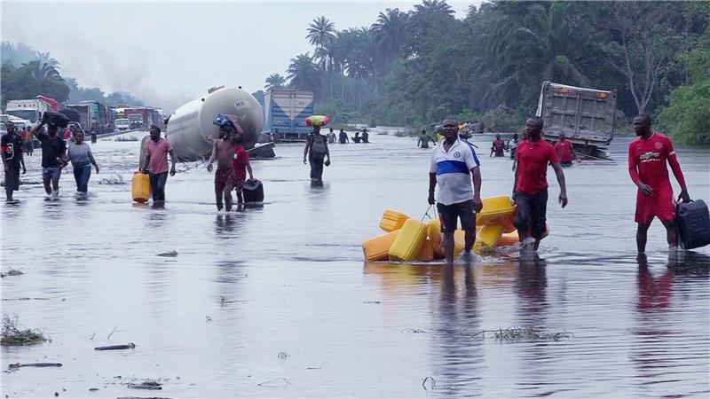 Menschen im nigerianischen Bayelsa waten durch überflutete Straßen.