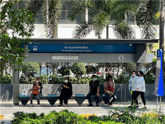Menschen kühlen sich im Schatten einer Bushaltestelle in Bangkok ab.