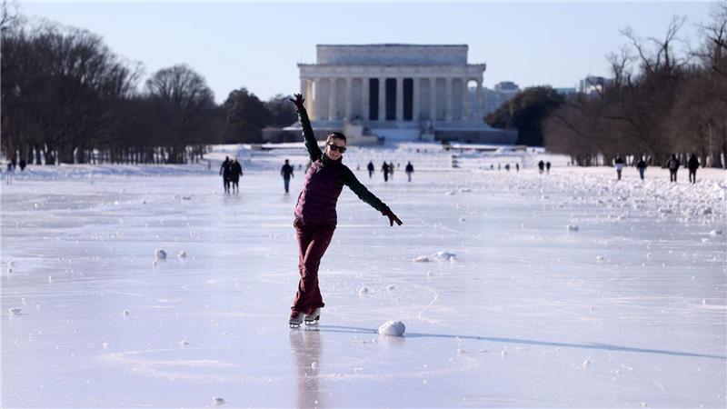 Menschen laufen Schlittschuh auf dem zugefrorenen Wasserbecken vor dem Lincoln Memorial.