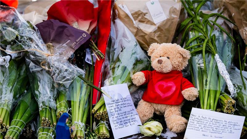 Menschen legen Blumen, Teddys und Botschaften am Brandort ab.