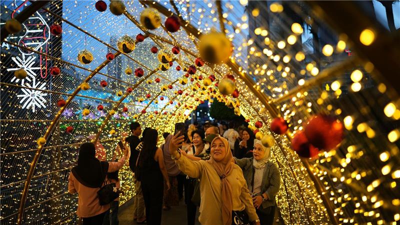 Menschen machen Selfies unter einer Weihnachtsbeleuchtung in Jakarta.