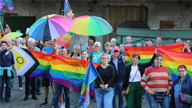 Menschen mit Regenbogenflaggen und -schirmen beteiligten sich an einer Kundgebung.