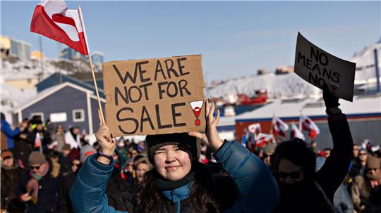 Das Foto zeigt eine Protestaktion vor dem US-Konsulat in Grönland. Eine junge Grönländerin hält im Vordergrund ein Plakat in die Höhe mit folgender Aufschrift: "We are not for sale" - "Wir stehen nicht zum Verkauf". 