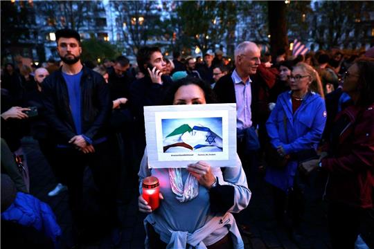 Menschen nehmen vor der Synagoge am Berliner Fraenkelufer an einer Mahnwache teil.