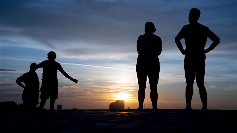 Menschen schauen sich am frühen Morgen den Sonnenaufgang auf dem Olympiaberg an.