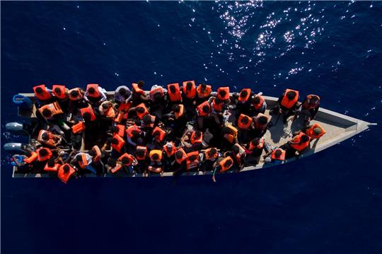 Menschen sitzen in einem Holzboot im Mittelmeer. Symbolbild