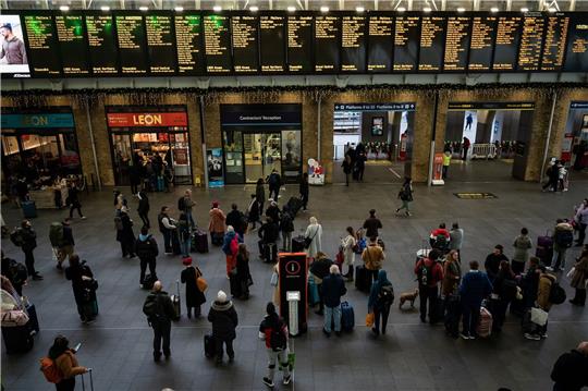Menschen stehen an Anzeigetafeln im Bahnhof Kings Cross in London. Streiks behindern den Reiseverkehr zu Weihnachten erheblich.