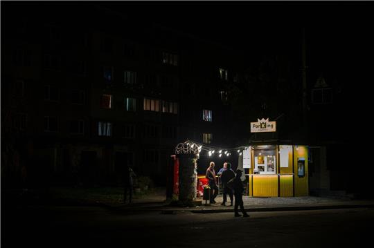Menschen stehen an einer Straße vor einer beleuchteten Bar. In der Ukraine greift Russland weiter gezielt Kraftwerke und andere Infrastruktur an.