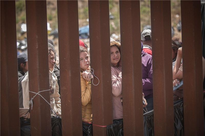 Umstrittene Abschiebepraxis in den USA beendet Menschen stehen hinter der Grenzmauer zwischen Mexiko und USA und hoffen darauf, in die USA einreisen zu können.