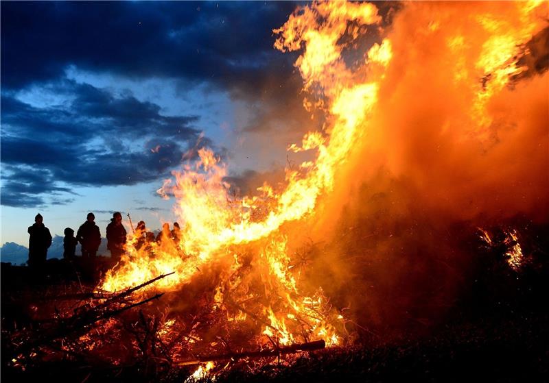 Menschen stehen um ein traditionelles Osterfeuer.