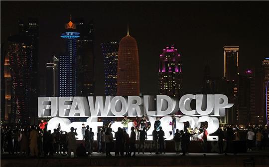 Menschen stehen vor der Eröffnung der WM vor einem beleuchteten Schriftzug «Fifa World Cup Qatar 2022».