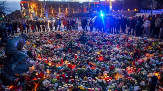 Menschen stehen vor der Johanniskirche an dem ein Gedenkort eingerichtet wurde und an dem vor dem Portal Blumen und Kerzen niedergelegt wurden. Am 20. Dezember ist auf dem Weihnachtsmarkt in Magdeburg ein Autofahrer in eine Menschengruppe gefahren. Es gab mehrere Tote und Verletzte.
