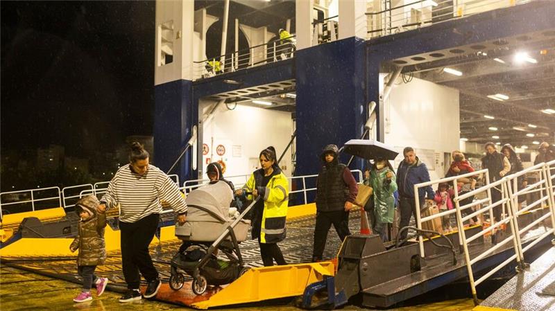 Menschen steigen im Hafen von Piräus von einer Fähre, mit der sie Santorini verlassen haben.