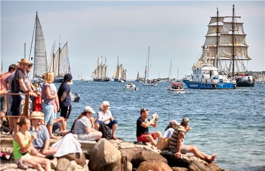 Menschen verfolgen an der Förde die Windjammerparade.