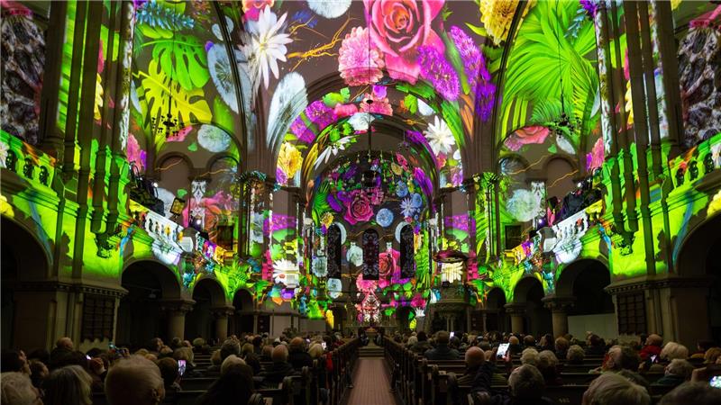 Menschen verfolgen in der Dresdner Martin-Luther-Kirche eine Lichtshow.