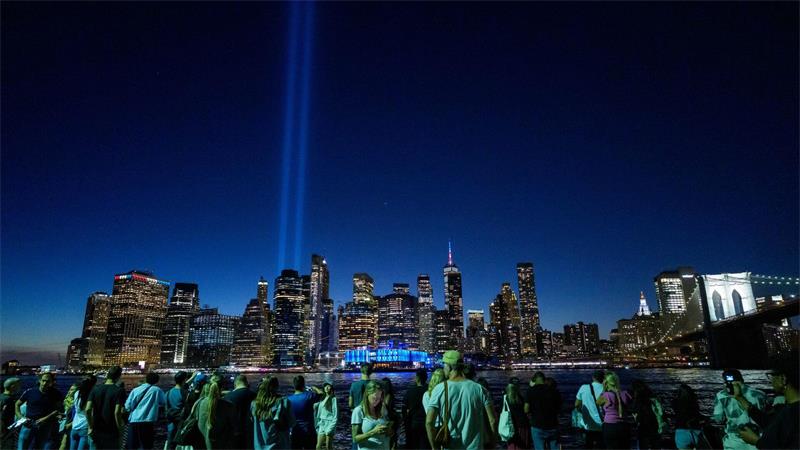 Menschen versammeln sich am 25. Jahrestag der Terroranschläge vom 11. September 2001 im New Yorker Stadtteil Brooklyn, um das Lichtspektakel „Tribute in Light“ zu beobachten, das über Lower Manhattan strahlt.