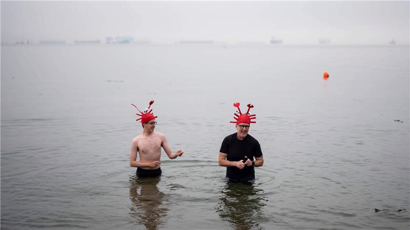 Menschen waten im Wasser während des olar Bear Swim in Vancouver.