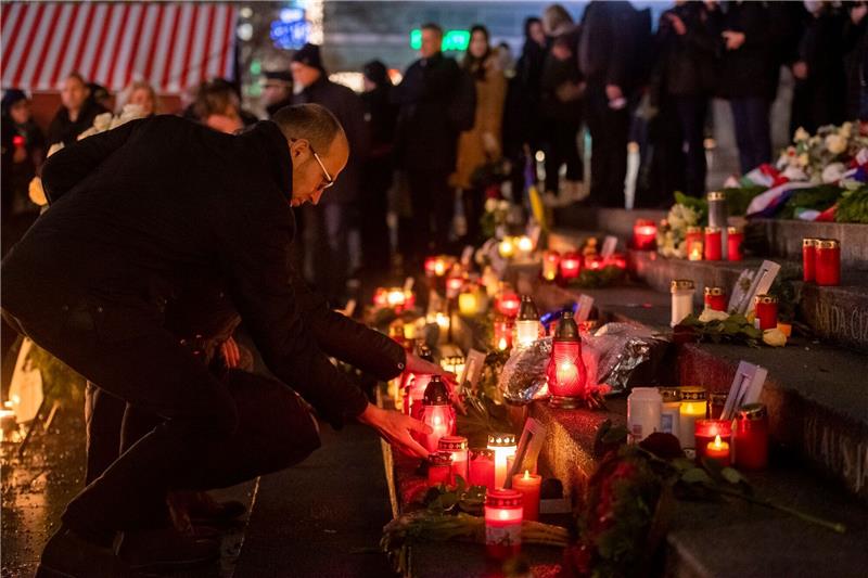 Glocken und weiße Rosen erinnern an Opfer von Terroranschlag Menschen zünden bei der Gedenkveranstaltung zum Terroranschlag auf dem Berliner Breitscheidplatz an der Gedächtniskirche Kerzen an.