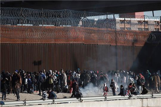 Migranten aus Lateinamerika stehen an der Grenzmauer zwischen Mexiko und den USA.