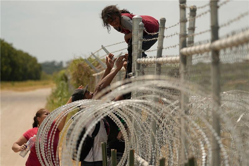 Rekord bei illegalen Einreisen von Familien in die USA Migranten, die den Rio Grande von Mexiko in die USA überquert haben, klettern in Texas über einen Zaun mit Stacheldraht.