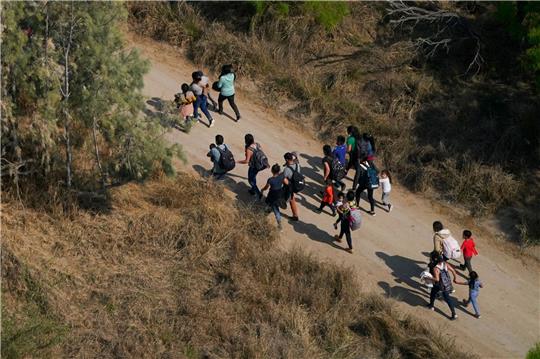 Migranten gehen einen Feldweg entlang, nachdem sie die Grenze zwischen den USA und Mexiko überquert haben.