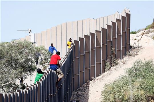 Migranten klettern über einen Zaun auf der Insel Lampedusa.