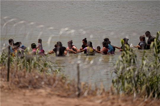 Migranten überqueren Hand in Hand den Fluss Rio Grande.