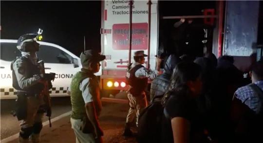 Migranten verlassen im Beisein von Sicherheitskräften den Lastwagen - die meisten von ihnen stammen aus Guatemala.