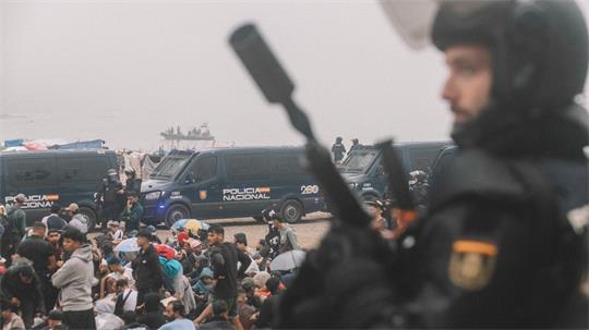 Migranten wurden in Ceuta von starken spanischen Polizeikräften von einem Hüttenlager am Strand fortgebracht. 