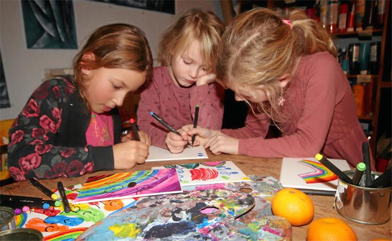 Milla, Hannah und Lena malen gemeinsam in Zinglers Kunst-Küche an einem Bild.