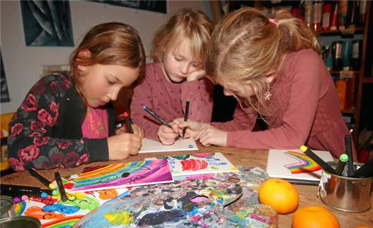 Milla, Hannah und Lena malen gemeinsam in Zinglers Kunst-Küche an einem Bild.