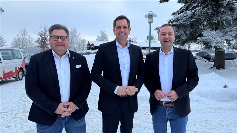 Das Foto zeigt drei Männer vor einer verschneiten Landschaft.
