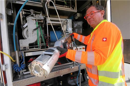 Mirko Muschallik präsentiert das Spezialfahrzeug, das gleich herabgelassen wird, um durch die Kanäle der Friedrich-Ebert-Straße in Schladen zu fahren und Bilder zu liefern. Foto: Gereke