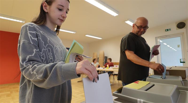 Wähler stecken Wahlzettel in eine Wahlurne.