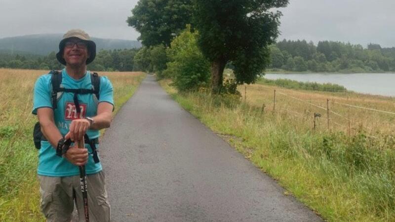 Ein Mann steht auf einem Weg an einem Teich.