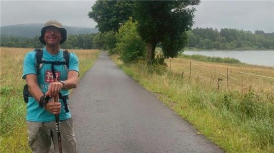 Ein Mann steht auf einem Weg an einem Teich.