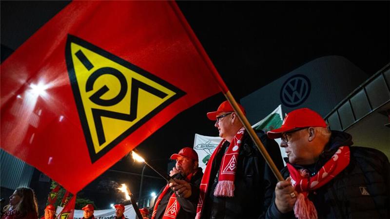 Warnstreiks an zahlreichen Werkstoren in Niedersachsen Mit Gewerkschafts-Fahnen stehen Mitarbeiter vor dem Volkswagen-Werk.