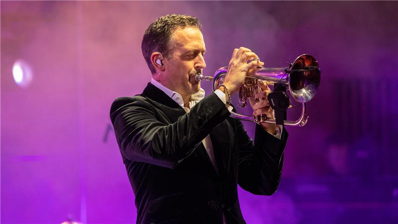 Till Brönner kommt – aber wohin? Kaiserpfalzkonzerte vor Ortswechsel Mann mit Augen zu spielt Trompete im Anzug. Der Hintergrund ist lila.