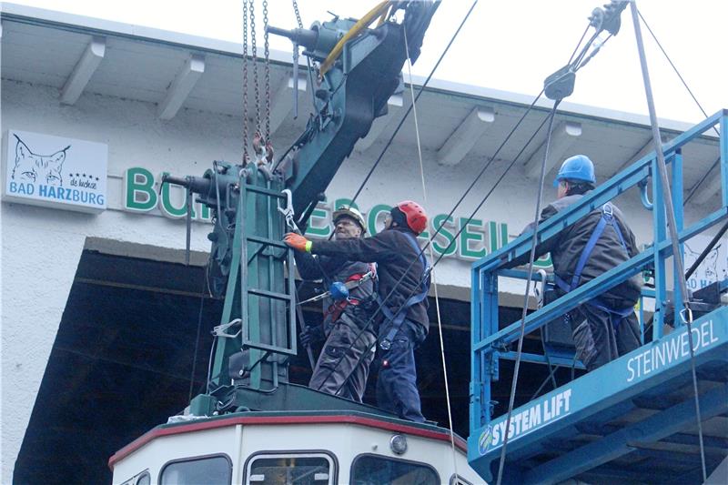Mit Kraft und Fingerspitzengefühl lösen Seilbahn-Chef Oliver Busch (M.) und sein Team die Traverse aus dem Seil. Mit einem Kran ist die Gondel gesichert und wird anschließend behutsam zu Boden gelassen. Foto: Nachtweyh